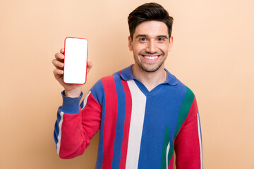 Wall Mural - Photo of young smiling guy promoter holding smartphone touchscreen advertisement download mobile app isolated on beige color background