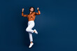 © deagreez - Full size photo of attractive young woman jump celebrate win dressed stylish brown silk formalwear isolated on dark blue color background
