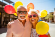 Outdoor portrait of a happy elderly couple with sunglasses wearing colorful shirts holding balloons