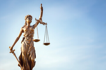 Legal law concept statue of Lady Justice with scales of justice with blue sky background