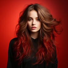 Beautiful Fashion Model With Creative Long Curly Hair, Studio Shot. Portrait Of Beautiful Young Woman In Black Clothes With Red Hair On Red Background. Portrait Of A Fashion Model With Bright Makeup.
