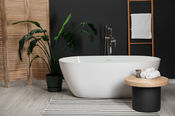 Sticker - Spa day. Ceramic tub, houseplant and wicker table in bathroom