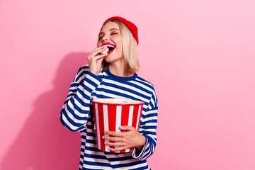 Wall Mural - Photo of excited dreamy girl dressed striped shirt eating pop corn wathcing movie empty space isolated pink color background