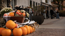 Pumpkins In Old Cart On Shoppingstreet As Outdoor Halloween Decoration, Whit People Shopping In The Background.