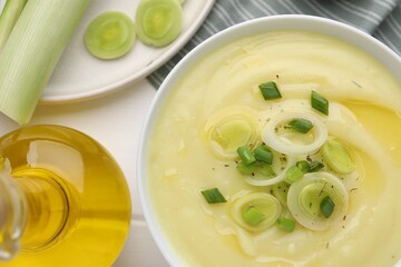 Poster - Bowl of tasty cream soup with leek on wooden table, flat lay