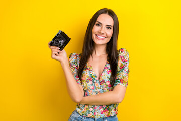 Canvas Print - Photo of satisfied cheerful girl with long hairdo dressed flower print blouse hand holding camera isolated on yellow color background