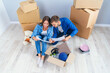 © gorynvd - Couple have a discussion about design of their new home sitting on the wooden floor between many cardboard boxes. Beautiful young stylish couple in love planning home design for their new bought flat.