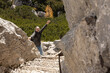 © Guzel - Gray-haired man with long hair standing, holding on to a metal railing and raising his hand in greeting, Austria