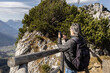 © Guzel - Gray-haired man with backpack standing on steep mountain slope and taking pictures of picturesque mountain landscape