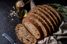 Sliced Sourdough Bread From Whole Grain Flour And Pumpkin Seeds On A Grid, Olive Oil And Black Olive On A Rustic Wooden Table. Artisan Bread.