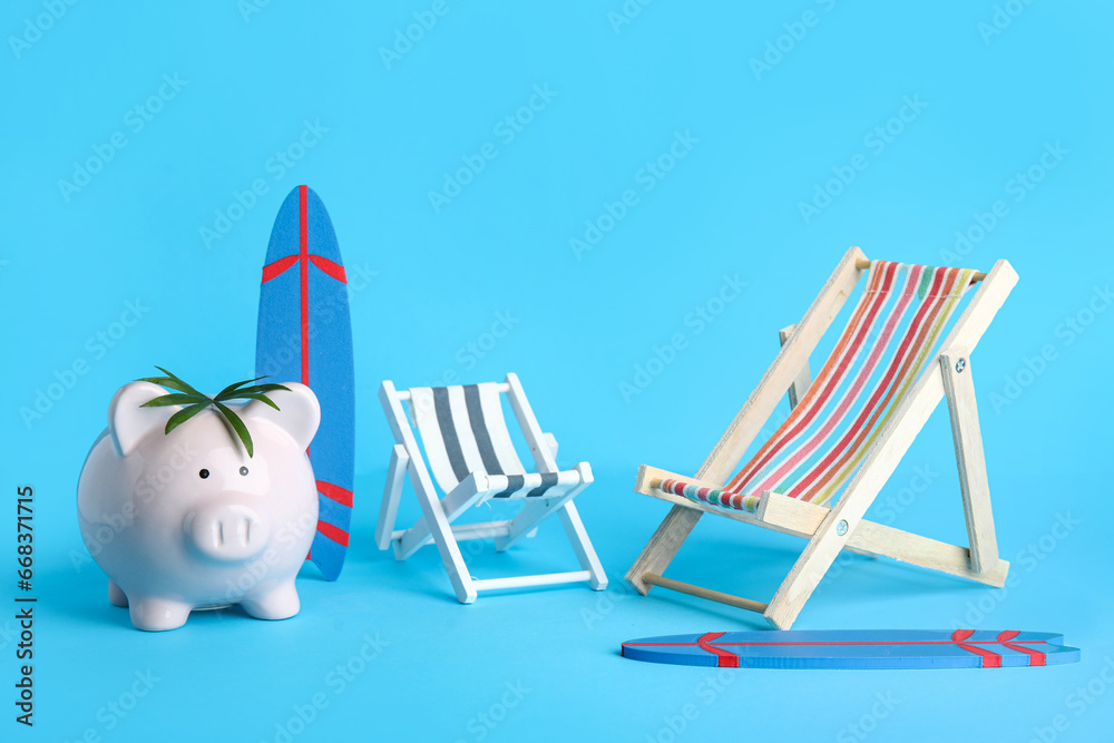 Piggy bank with surfboards and deck chairs on blue background