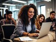 © DigitalArt - A joyful young woman with curly hair works on her laptop in a modern office setting, surrounded by focused colleagues.