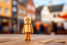 A Small Wooden Figure Is Standing On A Table. Blurred City, Urban Background.