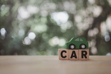 Wall Mural - Close up car wooden text placed on a green toy car. The concept of a car with copy space