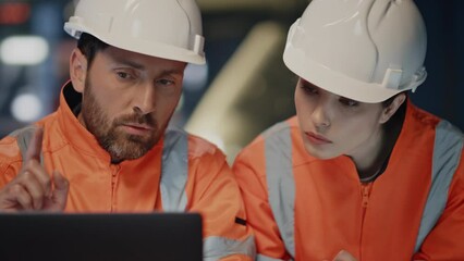 Wall Mural - Focused engineers looking laptop checking production project on factory close up