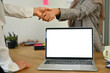 © Prathankarnpap - Shot of two businesspeople shaking hands over laptop computer with blank screen