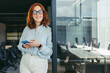 © Jacob Lund - Professional businesswoman smiling and using her smartphone in a tech office