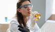 © H_Ko - Female chimist in white protective gloves drink beer from test tube portrait. Food test concept