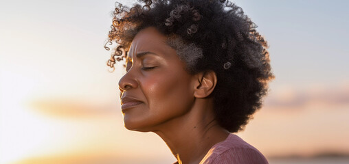 Close up lifestyle portrait of exhausted and stressed middle aged black woman standing outside with sky background