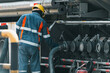 oil and gas workers fueling large fuel-truck, tanker inside refinery., Fueling Up a Freight Transport Truck