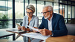 © Joshua - Two professional executives discussing financial accounting papers working with paperwork in office. Mature business woman and man managers holding legal corporate documents at meeting