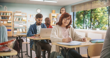 Leinwandbilder - Diverse Mature Students Learning in Classroom, Using Laptops and Writing in Notebooks. Senior Female Motivated to Learn New Skills During Adult Education Course in School, Completing An Assignment.