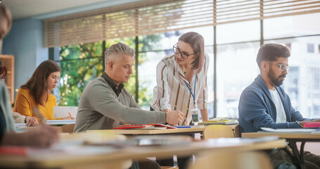 Poster - Young Female Teacher Giving a Lecture During an Adult Education Course in School, Having a Conversation with a Middle Aged Man. Diverse Mature Students Doing Textbook Exercises in Classroom