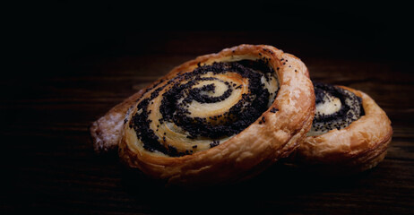 Two delicious buns with poppy seeds on a dark background.