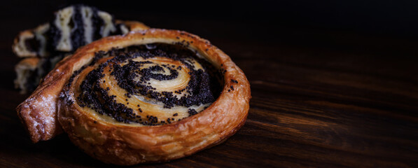 Two poppy seed buns whole and cut on a wooden background.