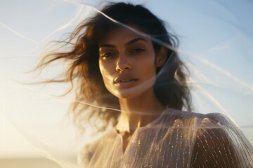 Wall Mural - A beautiful Latina woman in a modern dress at the beach at the golden hour. A shot of a model in a magazine-style fashion film photograph