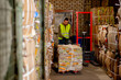 A worker using a stacker lifts and transports a cargo cardboard box with things for recycling at garbage station