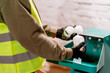Close-up shot of male hands in gloves pouring plastic caps into shredding apparatus for recycling