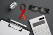 Red awareness ribbon with doctoral supplies on dark background. Medicine. Worlds HIV Aids Day. Flat lay