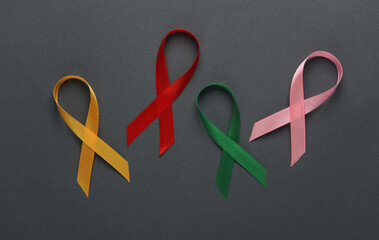 Red, pink, yellow, green awareness ribbons on dark background