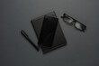 Leather notepad with smartphone, pen and eyeglasses on dark background. Top view