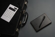 Leather suitcase with calculator and notebook on a dark background. Business concept.