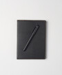 Notebook with black leather cover and pen on white background