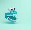 © splitov27 - Fanged jumping jaw with eyes flying in antigravity on blue background with shadow. Levitation object in the air. Halloween minimal layout