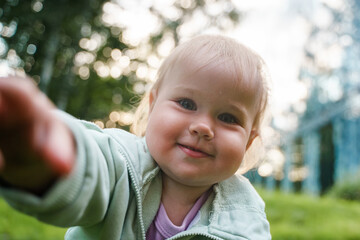 Wall Mural - Cute blonde babe kid baby crawls right into the camera face in the park