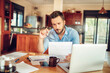 © Geber86 - Concerned young man reading through bank statements at home