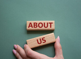 Sticker - About us symbol. Wooden blocks with words About us. Beautiful grey green background. Businessman hand. Business and About us concept. Copy space.