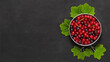 Frische Beeren auf edlem Dunkel: Rote Heidelbeeren in einer Schüssel auf einem stilvollen Tisch – gesunder Genuss in eleganter Atmosphäre.