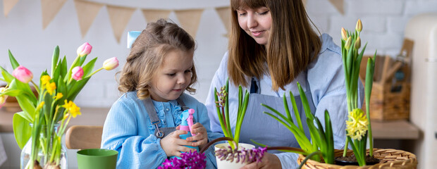 Happy mother and daughter doing home gardening together in the kitchen, taking care about flowers, plants. Family traditions, quality time, fun, enjoy domestic life. Mother's or Women's day. Banner