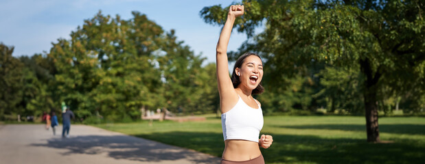 Wall Mural - Hooray, victory. Smiling asian girl triumphing, celebrating achievement, running till finish, shouting from excitement