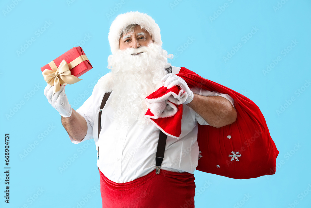 Santa Claus with bag and Christmas gift on blue background
