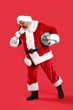 © Pixel-Shot - Cool Santa Claus with disco ball and microphone singing Christmas song on red background