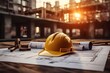 Yellow hard hat and blueprint on wooden table in construction site background.