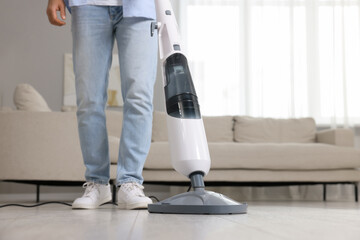 Sticker - Man cleaning floor with steam mop at home, closeup. Space for text