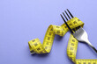 © New Africa - Fork with measuring tape on purple background, top view with space for text. Diet concept