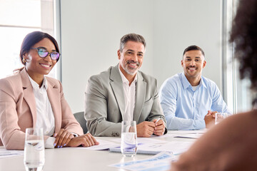 Happy diverse executive business people group working together at meeting in boardroom office. International busy board team colleagues company employees collaborating consulting at conference table.